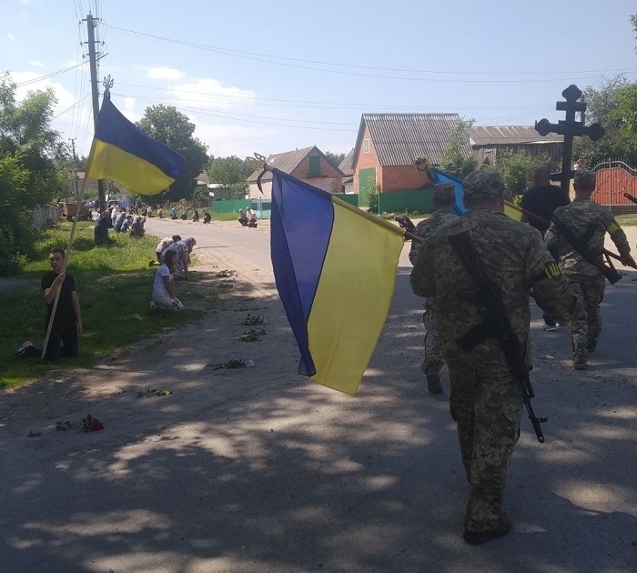 ПИсарівчани стають на коліна, віддаючи шану загиблому воїнові