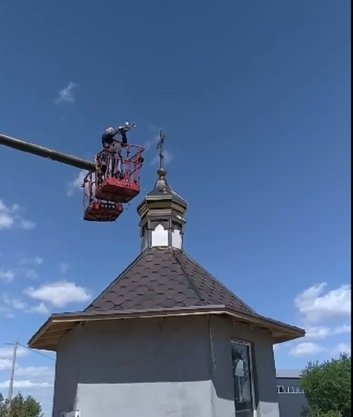 Петро Чешківський грає  на трубі мелодію "Ой у лузі червона калина" після встановлення хреста на бані.