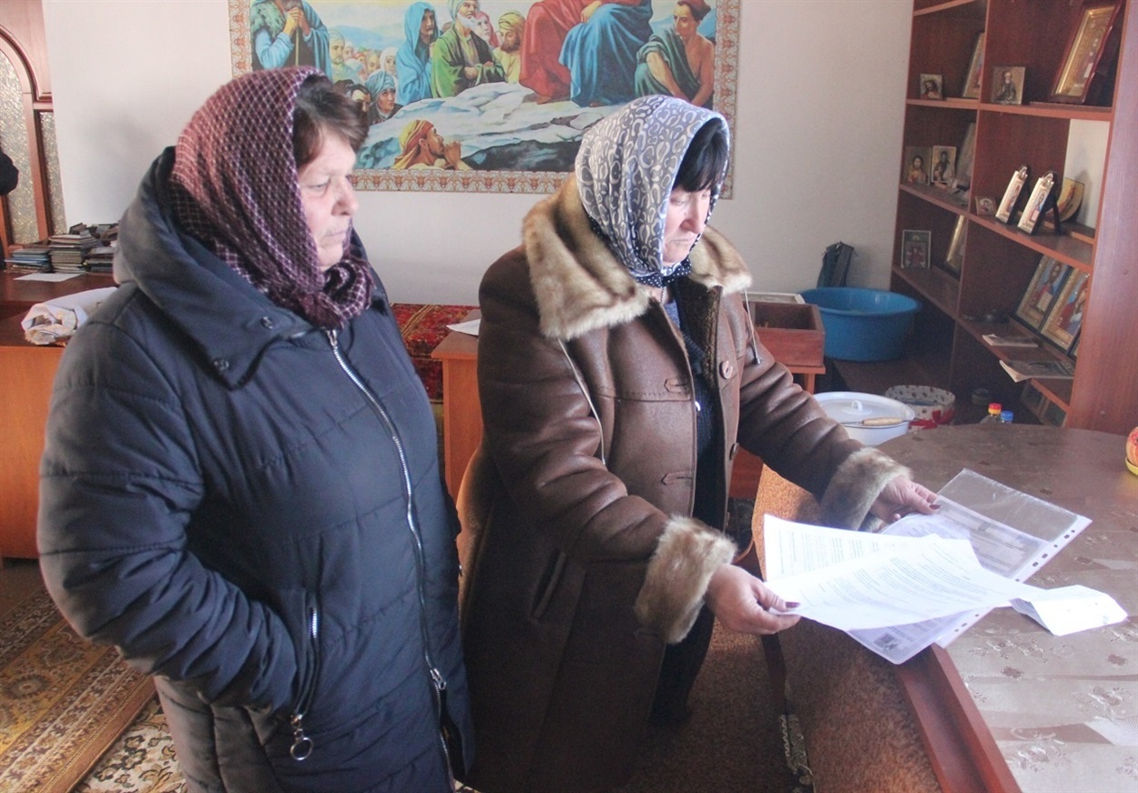 Неля Суша (праворуч) показує документа про реєстрацію релігійної громади