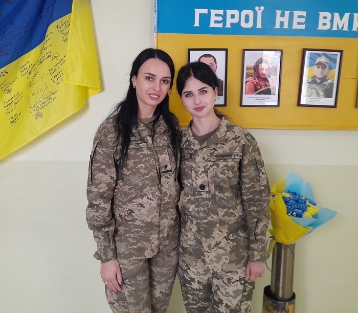 Вікторія Гуріненко та Владислава Поліщук біля стенду  випускникам Пиківської школи, які загинули у боях з російськими окупантами.